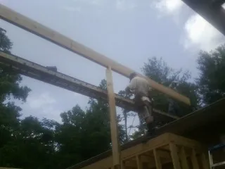 Carpenter setting a ridge beam over a new addition frame — Ice Dam Removal by Roofing Brothers in Hornell
