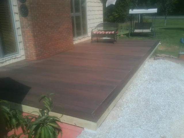 Freshly stained wood deck built against a brick home in Hornell
