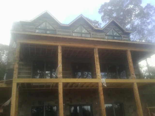 Dormers and porch framing on a large log home under construction — Roof Coating work by our crew in Hornell