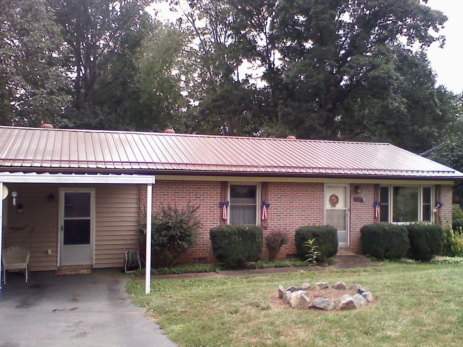 Bronze metal roof and carport on a brick ranch home — Roof Repair work by our crew in Hornell